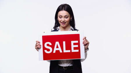 Excited real estate agent looking at signboard with sale lettering isolated on whiteの写真素材