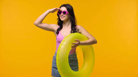 Smiling woman with swim ring looking away isolated on yellowの写真素材