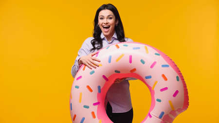 Excited businesswoman holding swim ring isolated on yellow
