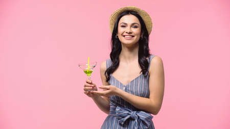 Pretty woman in straw hat holding cocktail with drinking straw isolated on pink