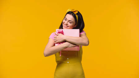 Happy woman hugging present isolated on yellowの写真素材