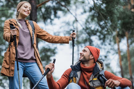happy couple with hiking sticks resting after trekking in forestの写真素材