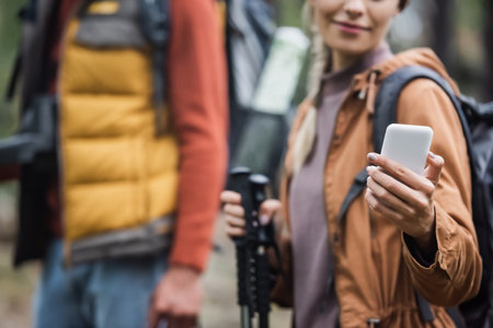 cropped view of smiling woman holding smartphone near blurred boyfriendの写真素材