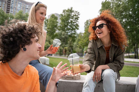 excited woman in sunglasses giving refreshing cocktail to man outdoors