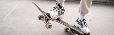 partial view of man in sneakers riding skate, banner