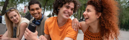 excited man holding portable music speaker near young interracial friends, banner