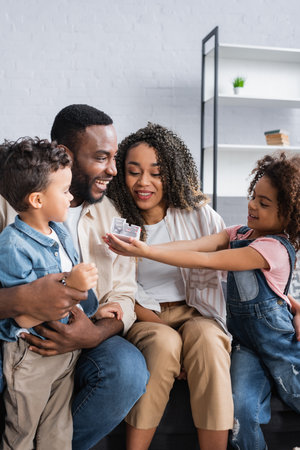 african american girl showing house model to smiling parents and brotherの写真素材