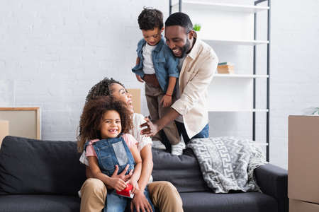 cheerful african american couple looking at each other near kids in new apartmentの写真素材