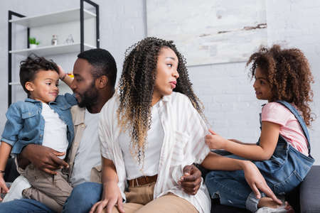positive african american family talking while sitting on sofa at home
