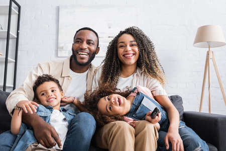 african american family laughing while watching comedy at homeの写真素材