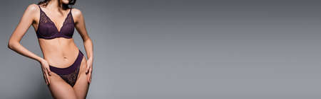 cropped view of sexy woman in lace purple underwear posing isolated on gray, bannerの写真素材