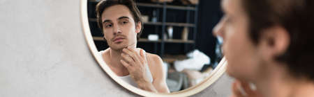 unshaven man touching bristle on face near mirror, bannerの写真素材