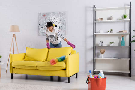 Young african american woman cleaning couch near dust brush and detergentsの写真素材