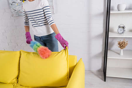 Cropped view of woman cleaning couch during housework