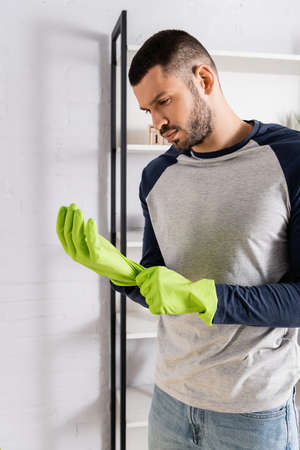 Young man wearing rubber gloves at homeの写真素材