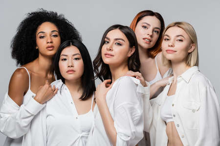 asian and curly african american models in white shirts posing with women isolated on grayの写真素材