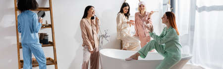 happy interracial women in eye patches smiling in bathroom during slumber party, bannerの写真素材
