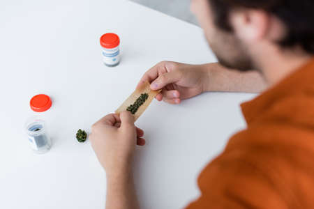 partial view of diseased man making joint with medical cannabis at homeの写真素材