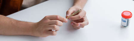 cropped view of ill man holding joint with medical cannabis, banner