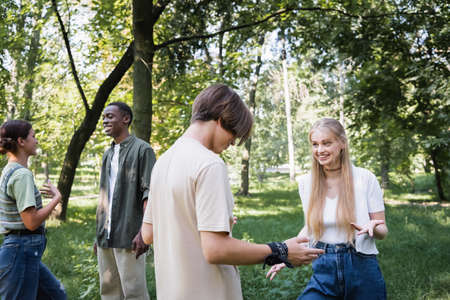 Smiling multiethnic teenagers talking in park during summer