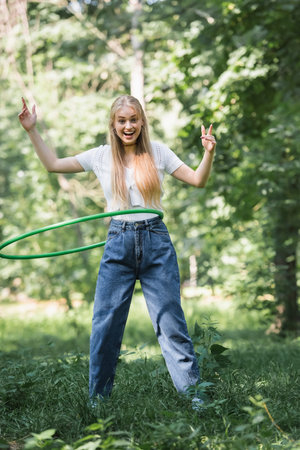 Smiling teenager twisting hoop and looking at camera in parkの写真素材