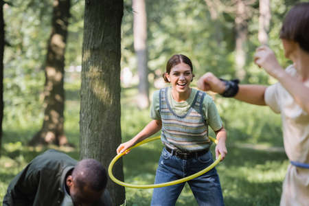 Smiling teenager holding hoop near interracial friends on blurred foregroundの写真素材