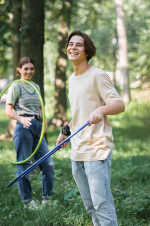 Positive teenager holding hoop near blurred friend