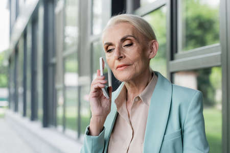 Senior manager holding smartphone near ear outdoorsの写真素材