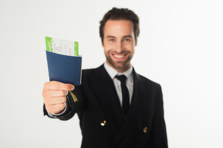 Passport with air ticket in hand of blurred aviator isolated on whiteの写真素材