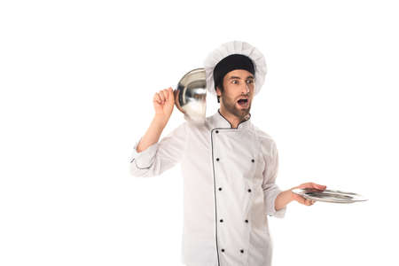 Amazed chef holding cloche near ear isolated on white