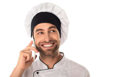 Positive chef in uniform talking on mobile phone isolated on whiteの写真素材