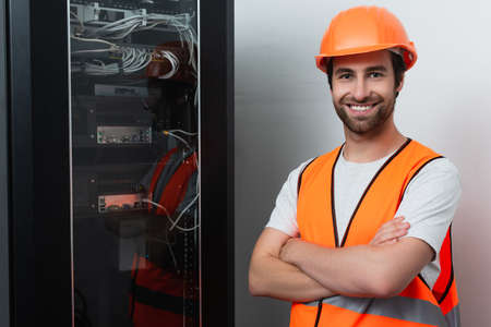 Smiling workman looking at camera near switchboardの写真素材