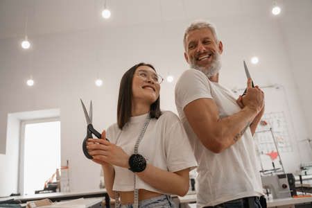 Low angle view of multiethnic designers holding scissors in workshopの写真素材