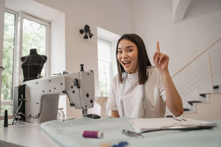 Asian designer having idea near sewing machine in atelierの写真素材