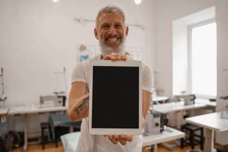 Smiling blurred designer holding digital tablet with blank screenの写真素材