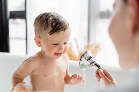 blurred mother holding shower head and bathing toddler sonの写真素材