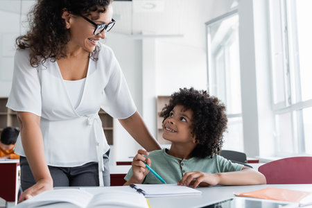 african american schoolboy an teacher looking at each other during lesson