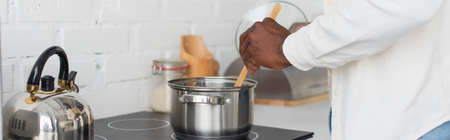 cropped view of young african american man cooking in kitchen, bannerの写真素材