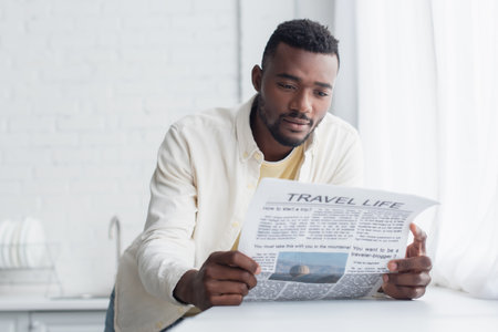 african american man in shirt reading travel life newspaperの写真素材