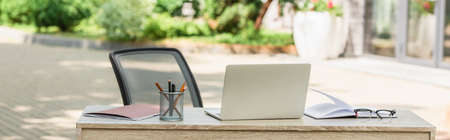 laptop near notebook and stationery on desk outside, bannerの写真素材