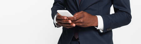 cropped view of african american businessman in suit messaging on smartphone isolated on gray, bannerの写真素材