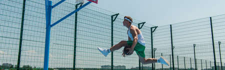 Side view of young sportsman with basketball ball jumping near hoop, banner