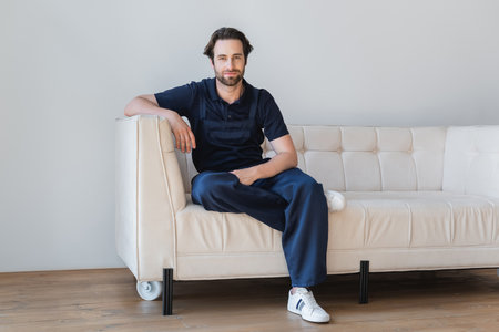 full length view of workman in overalls sitting on white couch