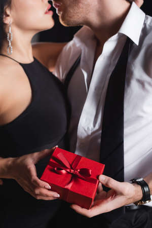 partial view of man holding gift box and kissing with woman in dressの写真素材
