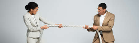businessman and businesswoman pulling rope isolated on gray, bannerの写真素材