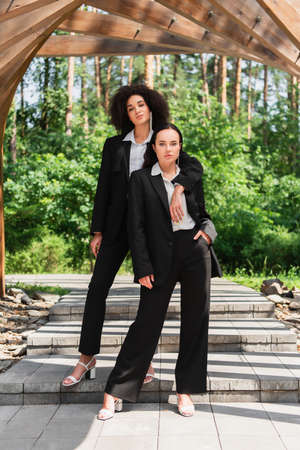 African american lesbian woman hugging girlfriend in suit outdoorsの写真素材