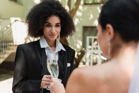 African american lesbian woman toasting champagne with blurred girlfriend during wedding outdoorsの写真素材
