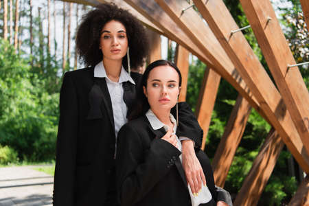 African american woman in suit hugging girlfriend outdoors