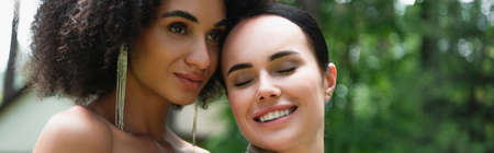 African american woman standing near smiling girlfriend outdoors, bannerの写真素材