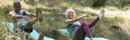 Positive interracial family training on fitness mats in forest, banner